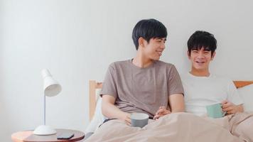 Asian Gay men couple talking having a great time at modern home. Young Asia lover LGBTQ male happy relax rest drink coffee after wake up while lying on bed in bedroom at house in the morning concept. photo