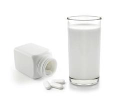 Pastilla y vaso de leche aislado sobre fondo blanco.