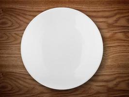 Empty white plate on wooden table photo