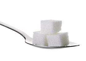 Cubitos de azúcares en una cucharadita aislado sobre fondo blanco.