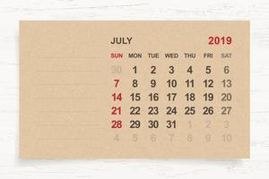 July 2019 - Monthly calendar on brown paper and wood background with area for note. Vector. vector