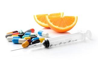 orange slice empty pill blister syringe and colorful pill and capsules on white background photo