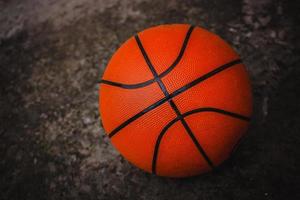 A dirty basketball on a concrete court after a street game. Dark background. photo