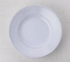 Empty white ceramic plate on wooden table photo