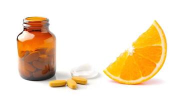 Fruta naranja con tableta de vitamina C y botella aislado en el fondo blanco. foto