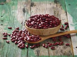 Frijoles rojos en el cuenco de madera sobre madera vieja foto