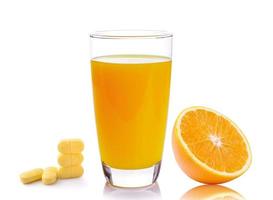 Vaso lleno de jugo de naranja y píldoras de vitamina C aislado sobre fondo blanco. foto