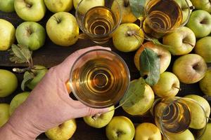 Female Hand With A Glass Of Apple Cider And Yellow Fruits Background. photo