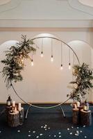 Wedding round arch in rustic style decorated with grass hay field color and retro light bulbs