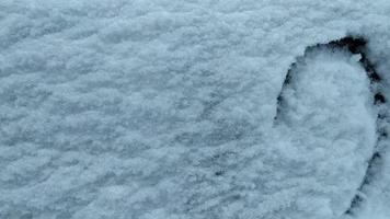 Draws a heart in the snow with her finger. video