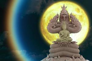 full moon corona light and Buddha sitting on  seven head of king naga on the night sky photo