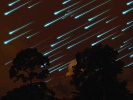 Meteorito en el cielo nocturno, nube de color naranja oscuro y árbol en el bosque tropical. foto
