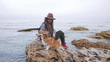 Mujer joven con perro corgi cerca del mar