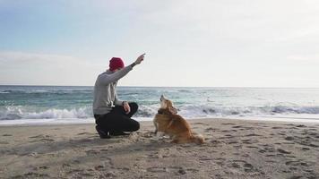 Mann spielt mit Hund am Strand