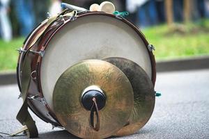 A bass drum with fanfare cymbals resting on the ground