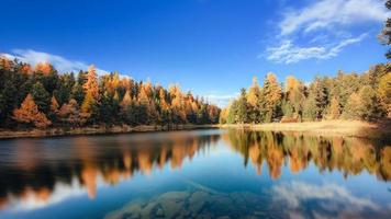 Paisaje otoñal con fantásticos colores de llanuras reflejadas en un lago alpino