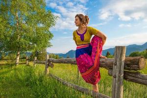 Casual girl relaxes doing stretching and yoga alone in the mountains over a fence in a beautiful spring meadow. photo