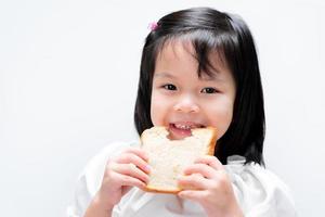 Happy child eat slices of bread. Simple breakfast. Isolated white background. Sweet smile kid. photo