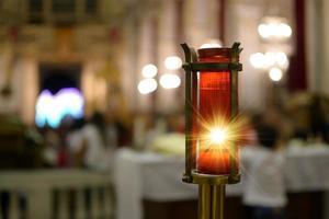 Vela votiva encendida dentro de una iglesia que representa la luz divina. Luz divina. foto