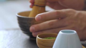 grüner Matcha-Tee, der auf einem schwarzen Steintisch zubereitet wird