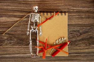 Autumn background with notepad, skeleton and dry leaves. Halloween card. photo