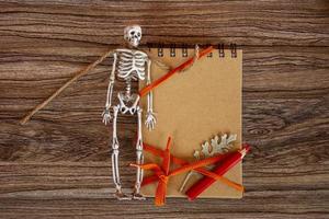 Halloween card. Autumn background with notepad, skeleton and dry leaves. photo