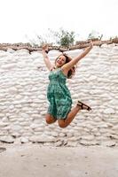 mujer joven saltando y celebrando en el fondo de la pared de ladrillo antiguo. foto