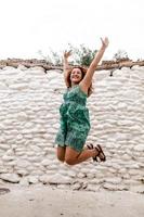 mujer joven saltando y celebrando en el fondo de la pared de ladrillo antiguo. foto