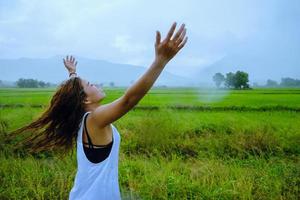 Asian women travel relax in the holiday.The girl smiled happy and enjoyed the rain that was falling. travelling in countrysde, Green rice fields, Travel Thailand. photo