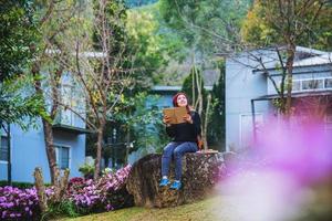 woman travel nature in the flower garden. relax sitting on rocks and reading books In the midst of nature at national park doi Inthanon. photo