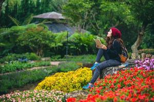 mujer viaje naturaleza en el jardín de flores. relájese sentado en las rocas y leyendo libros en medio de la naturaleza en el parque nacional doi inthanon.