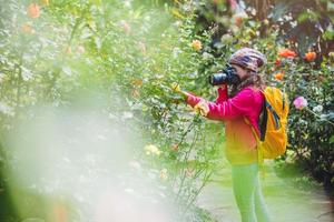 The girl standing holding the camera and  Photographing roses in the garden. photo