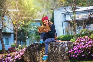 mujer viaje naturaleza en el jardín de flores. relájese sentado en las rocas y leyendo libros en medio de la naturaleza en doi inthanon. foto