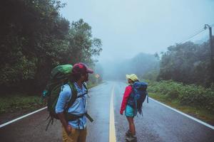 amante del hombre asiático y las mujeres asiáticas viajan por la naturaleza. caminar por la ruta de la carretera. viajando felizmente por la naturaleza. en medio de la neblina lluviosa.