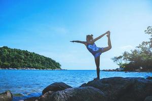 las mujeres asiáticas se relajan en las vacaciones. viajar relajarse. jugar si yoga. sobre las rocas junto al mar. en el verano. tailandia foto