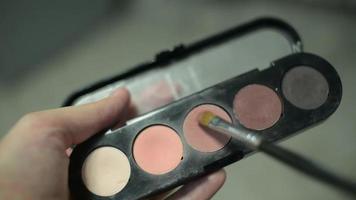 maquillador tomando una sombra de color de la paleta de sombras de maquillaje video