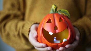 Halloween pumpkin lamp in children's hands. video