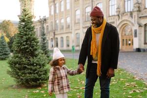 Black grandfather talking with his granddaughter outdoors during a walk photo