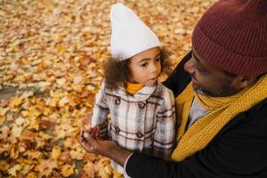 Abuelo y nieta negros divirtiéndose mientras juegan juntos en el parque de otoño foto