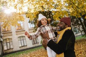 Abuelo y nieta negros divirtiéndose mientras juegan juntos en el parque de otoño foto