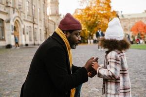 Abuelo negro hablando con su nieta durante caminar al aire libre foto