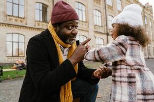 Black grandfather talking with his granddaughter during a walk outdoors photo