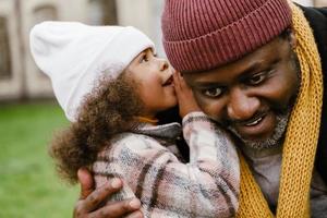 Black grandfather talking with his granddaughter during walking outdoors photo