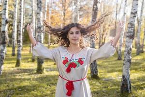 Bella mujer en ropa de traje tradicional nacional ucraniano en el bosque foto