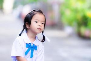 Adorable Asian little girl lift up at something. Female student stood waiting for her preparation to go to school. Child is 3 years old. photo