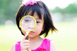 disparo a la cabeza. linda niña asiática mirando a través de gafas de oro vendiendo. niño de 4-5 años. foto