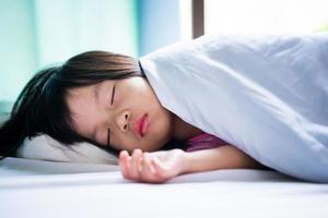 Retrato de muchacha hermosa asiática durmiendo en la cama blanca. bebé durmiendo en manta. niño de 4-5 años.