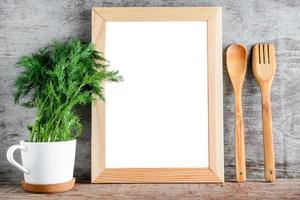 An empty wooden frame and kitchen accessories on a gray wall. photo
