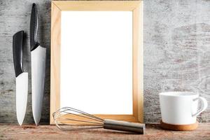 An empty wooden frame and kitchen accessories on a wooden background photo