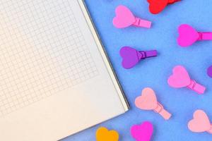 White paper and small colored hearts on a blue background. Concept notes for Valentine's Day photo